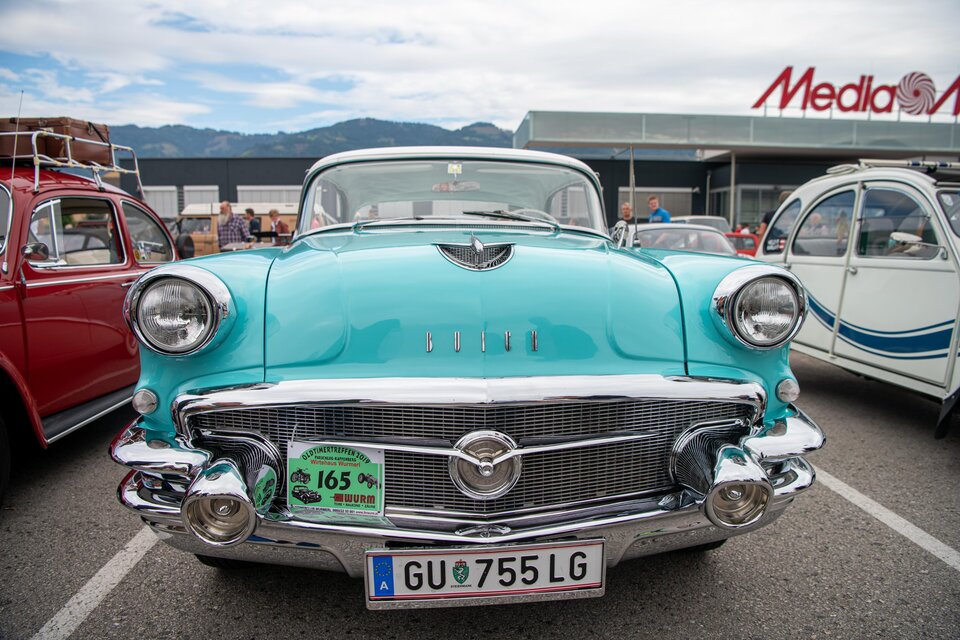 Ein klassisches Auto in leuchtendem Türkis mit glänzendem Chrom. Im Hintergrund sind weitere Oldtimer und ein klarer Himmel zu sehen. | © Ekaterina Paller