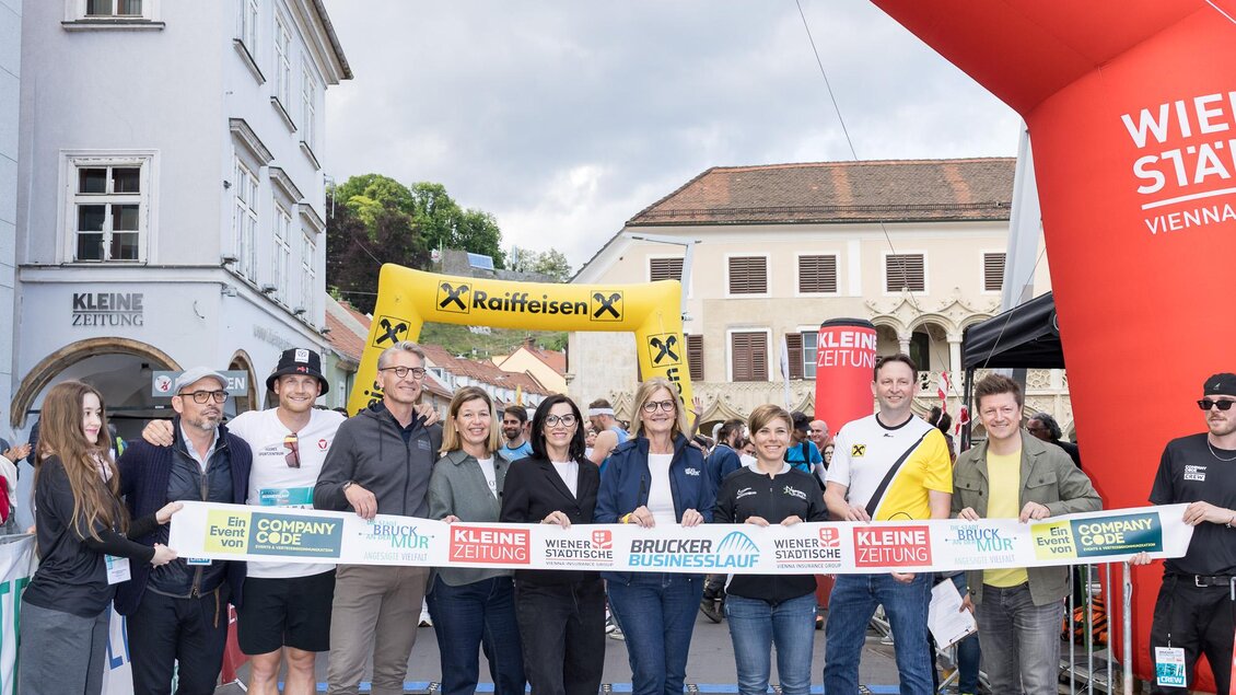 Eine Gruppe von Menschen steht unter einem roten Zielbogen mit der Aufschrift "Wiener Städtische". Sie halten ein Band, das abgeschnitten werden soll, um ein Event zu eröffnen. | © StadtBruck_Meieregger