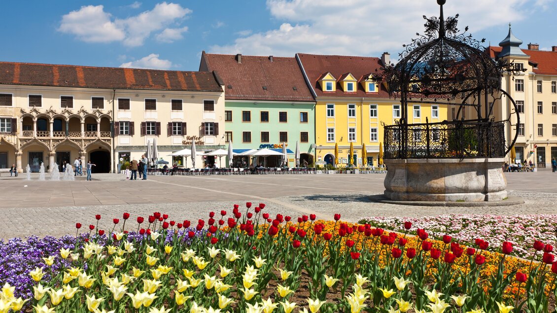 Ein schöner Platz mit bunten Blumenbeeten und historischen Gebäuden im Hintergrund. Die Architektur und das Blumenarrangement schaffen eine einladende Atmosphäre. | © TV Hochsteiermark, Harry Schiffer