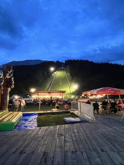 A festive scene on an unforgettable summer evening in the Ausseerland region with many stalls and lighting in front of the ski flying hill at Kulm. | © Auszeit Ausseerland