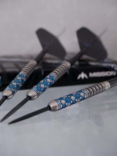 Drei Darts mit blauen und silbernen Griffen liegen neben einer schwarzen Verpackung. Die Darts sind präzise gestaltet und bereit zum Spielen. | © Pixabay.com