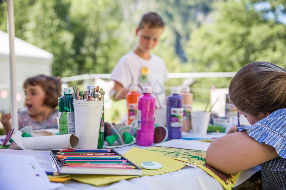 Ein kreativer Malbereich im Freien mit Kindern. Bunte Farben und Bastelmaterialien sind auf dem Tisch verteilt. | © Thomas Sattler - Gesäuse
