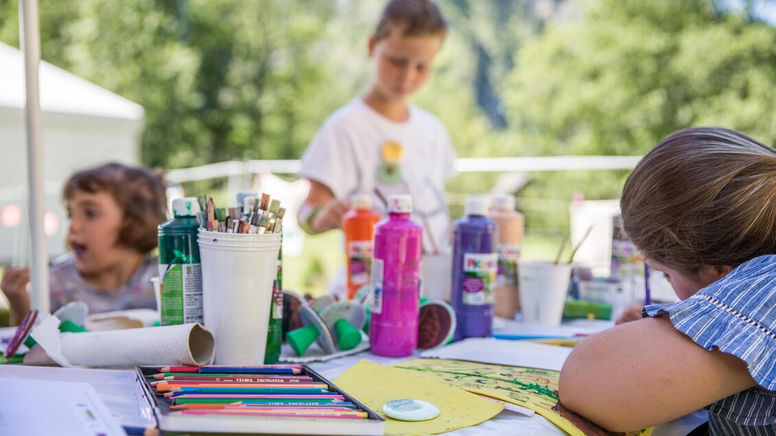 Ein kreativer Malbereich im Freien mit Kindern. Bunte Farben und Bastelmaterialien sind auf dem Tisch verteilt. | © Thomas Sattler - Gesäuse