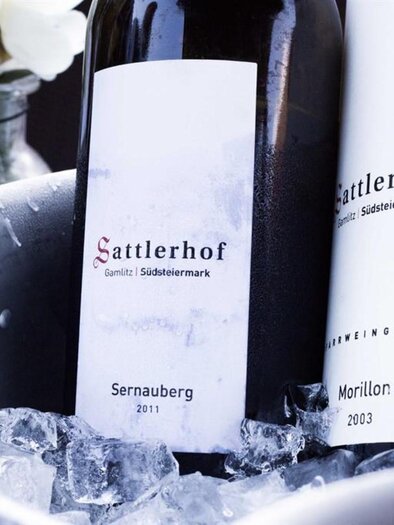 Two bottles of wine are standing in an ice bucket. The inscription "Sattlerhof" is clearly visible on the labels. | © Genießerhotel Sattlerhof