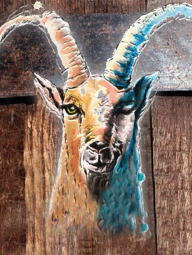 Ein kunstvolles Bild eines Ziegenkopfes mit großen Hörnern, das auf einem holzernen Hintergrund gemalt ist. Die Farben sind lebhaft und betonen die Details des Gesichts.