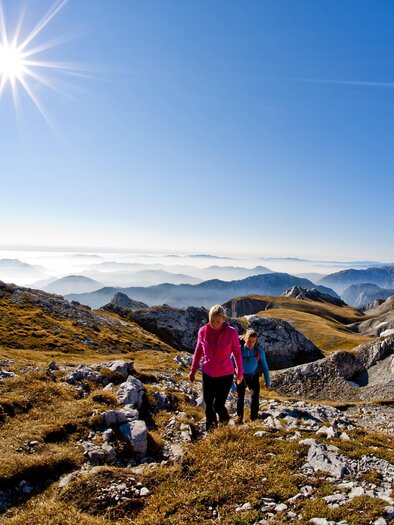 Das Bild zeigt ein Paar beim Wandern auf dem Hochschwab, Blauer Himmel, Sonnenschein und die hügelige Landschaft
