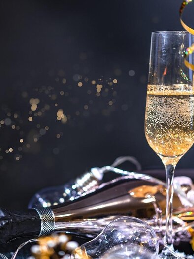 Zwei Sektgläser mit sprudelndem Champagner stehen auf einem Tisch. Um sie herum sind Luftschlangen und Glanzlichter zu sehen, die eine festliche Stimmung erzeugen. | © Pixabay.com