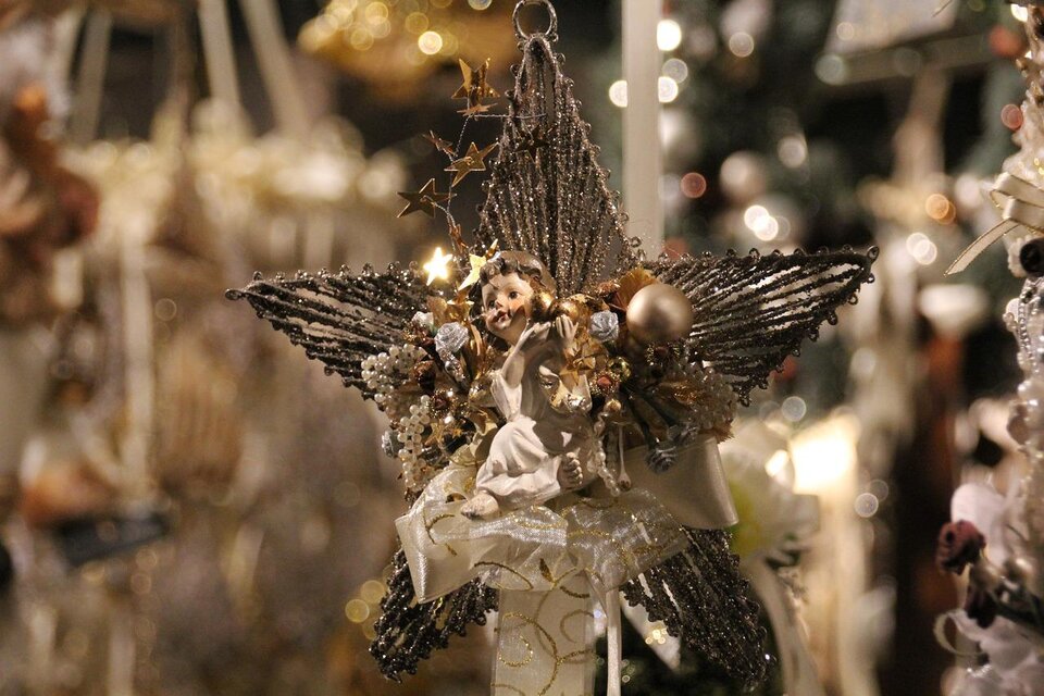 Ein glitzernder Weihnachtsstern mit einer kleinen Engelfigur in der Mitte. Der Stern ist mit vielen Farben und festlichen Dekorationen geschmückt.