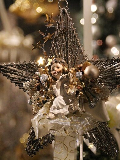 Ein glitzernder Weihnachtsstern mit einer kleinen Engelfigur in der Mitte. Der Stern ist mit vielen Farben und festlichen Dekorationen geschmückt.