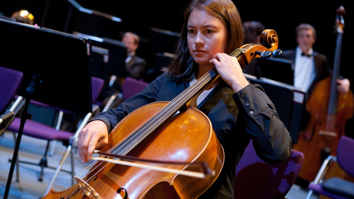 Eine Cellistin spielt in einem Orchester. Im Hintergrund sind weitere Musiker zu sehen. | © Graz Tourismus-Harry Schiffer