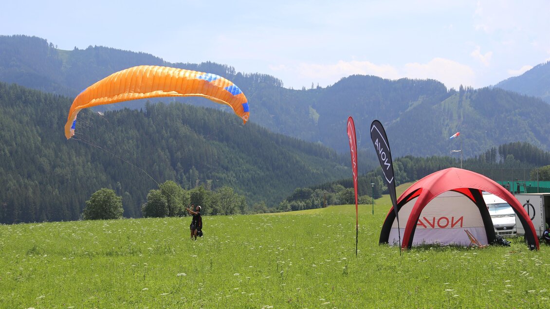 Ein Paraglider beim Landeanflug auf der Aflenzer  Bürgeralm. Danben steht in Info- oder Testzelt wo man sich über die Veranstaltung und Paragliding informieren kann. | © Paracenter Austria