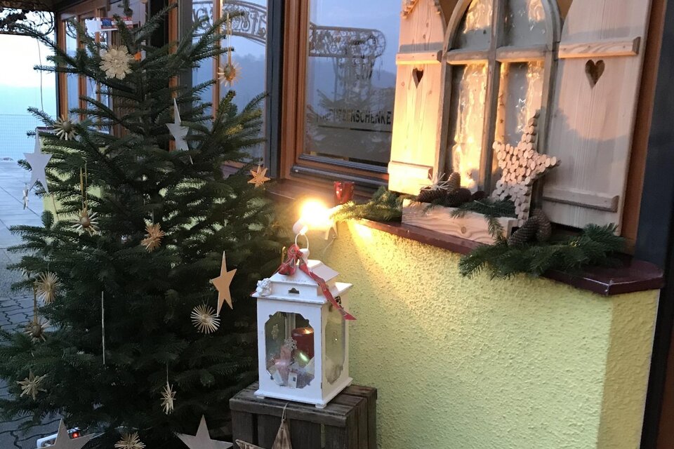 Weihnachtlich geschmückter Eingangsbereich beim Buschenschank Konrad mit Christbaum, leuchtendem Adventfenster und liebevoller Dekoration aus Holz und Naturmaterialien. | © Buschenschank Konrad