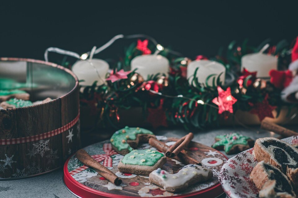 Ein Tablett mit festlichen Plätzchen und Lebkuchen. Im Hintergrund leuchten Kerzen und Dekorationen in weihnachtlichen Farben. | © pixabay.com