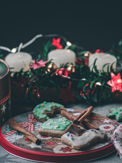 Ein Tablett mit festlichen Plätzchen und Lebkuchen. Im Hintergrund leuchten Kerzen und Dekorationen in weihnachtlichen Farben. | © pixabay.com