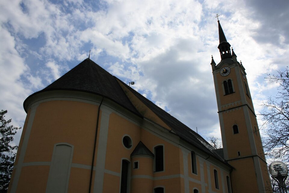 Eine historische Kirche mit einem hohen Turm und einem schönen gelben Anstrich. Der Himmel ist bewölkt, was der Szene eine ruhige Stimmung verleiht.