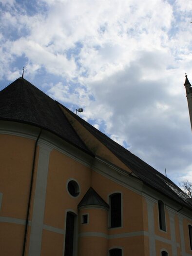 Eine historische Kirche mit einem hohen Turm und einem schönen gelben Anstrich. Der Himmel ist bewölkt, was der Szene eine ruhige Stimmung verleiht.