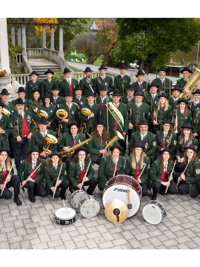 Group photo of the music club Hatzendorf in traditional costume with numerous female and male musicians along with their wind and percussion instruments. | © MV Hatzendorf