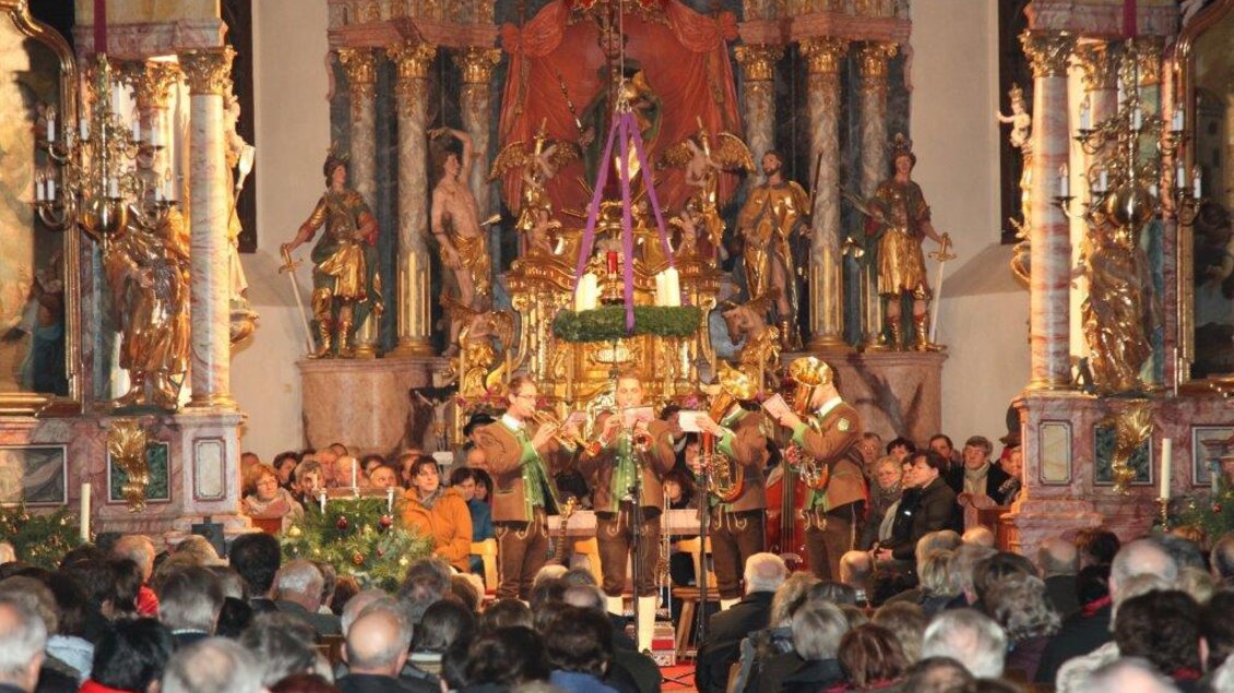 Eine festliche Veranstaltung in einer Kirche mit einer großen Menschenmenge. Auf der Bühne spielen Musiker vor einem kunstvoll dekorierten Altar. | © Gemeinde Gasen