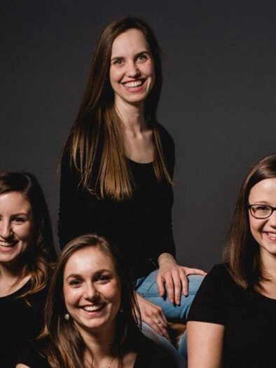 The vocal ensemble Puella, with four young ladies, poses for the picture. Against a black background. | © Theater & Kultur Premstätten