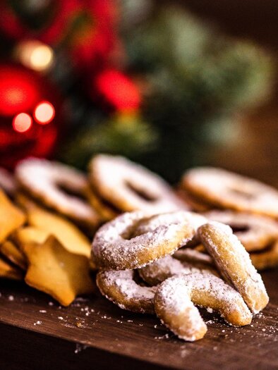 Leckere Weihnachtsplätzchen auf einem Holzbrett. Im Hintergrund sind Weihnachtsdekorationen zu sehen. | © Region Graz-Mias Photoart
