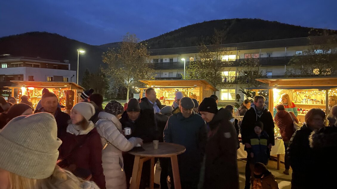 Besucher an beleuchteten Adventständen am Dorfplatz Stattegg bei Einbruch der Dunkelheit. | © Gemeinde Stattegg