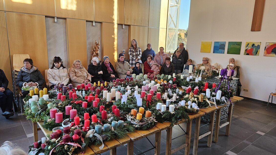 Zahlreiche Adventkränze mit bunten Kerzen bei der Adventkranzsegnung in Stattegg, dahinter Besucher. | © Gemeinde Stattegg
