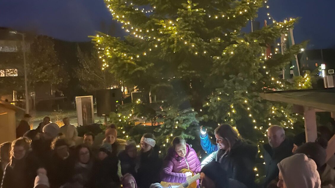 Besucher versammeln sich mit Musik vor dem beleuchteten Weihnachtsbaum am Dorfplatz Stattegg. | © Gemeinde Stattegg