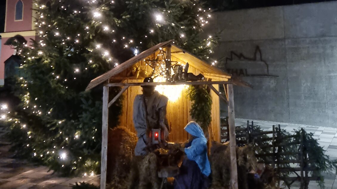 Eine Weihnachtskrippe mit Figuren von Maria und Josef in einem Stall. Im Hintergrund steht ein geschmückter Weihnachtsbaum. | © Marktgemeinde Thal