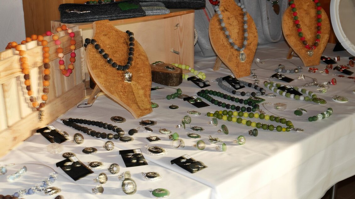 Eine Auswahl von handgefertigtem Schmuck liegt auf einem Tisch. Halsketten, Ohrringe und Ringe sind ordentlich angeordnet und zeigen verschiedene Farben und Materialien. | © Archiv Weinbauverein Klöch