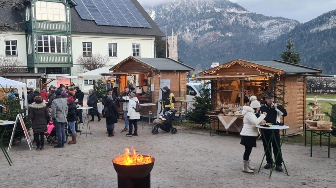 Ein Weihnachtsmarkt mit Holzhütten, in denen Stände angeboten werden. Menschen genießen das Fest in einer malerischen Berglandschaft. | © Winfried Büttner