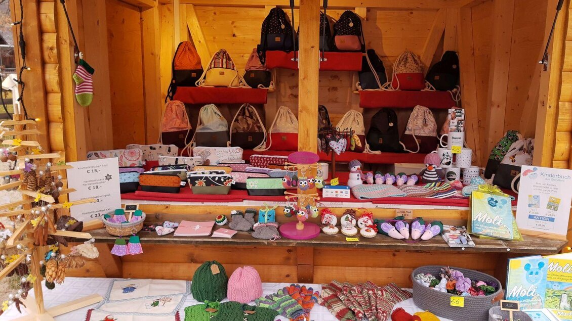 Ein gemütlicher Verkaufsstand mit verschiedenen handgemachten Taschen, Socken und Accessoires. Die Präsentation zeigt eine bunte Auswahl an gestrickten und genähten Produkten. | © Bettina Illmayer