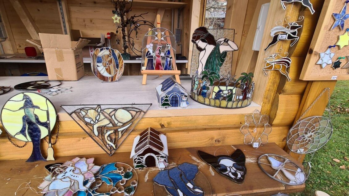 Eine Auslage mit bunten Glasobjekten in verschiedenen Formen und Designs. Die Stücke zeigen Tiere, Pflanzen und andere Motive auf einem Holztisch. | © Winfried Büttner