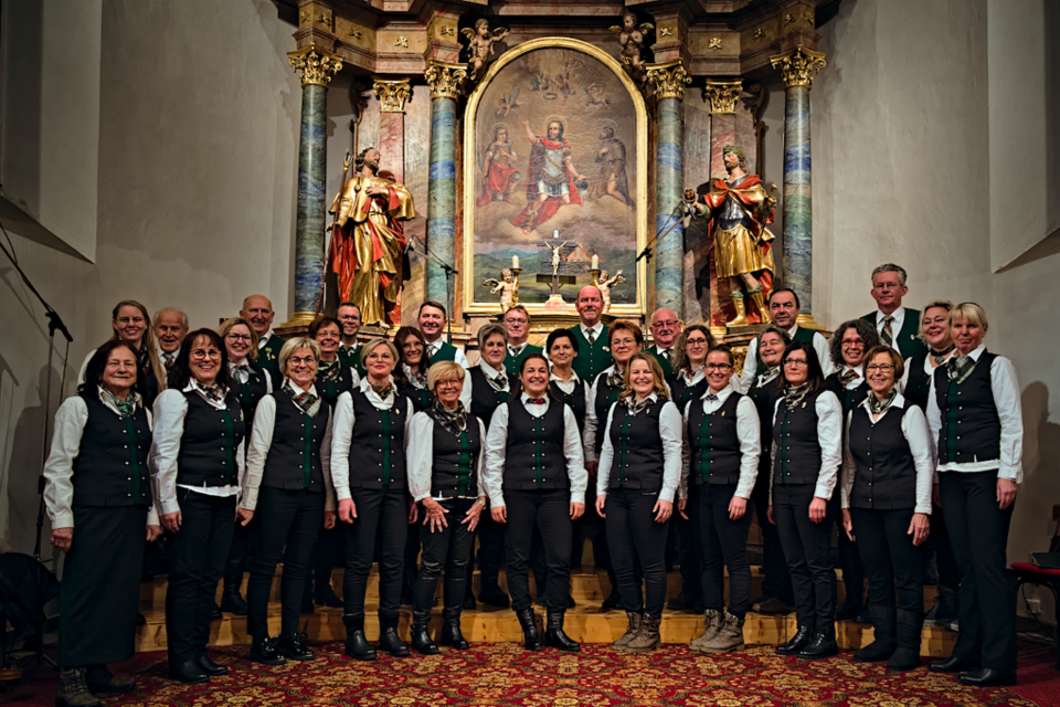 Eine Gruppe von Sängern steht in einer Kirche vor einem schönen Altar. Alle Mitglieder sind festlich gekleidet und lächeln in die Kamera. | © Gemischter Chor Bad Loipersdorf