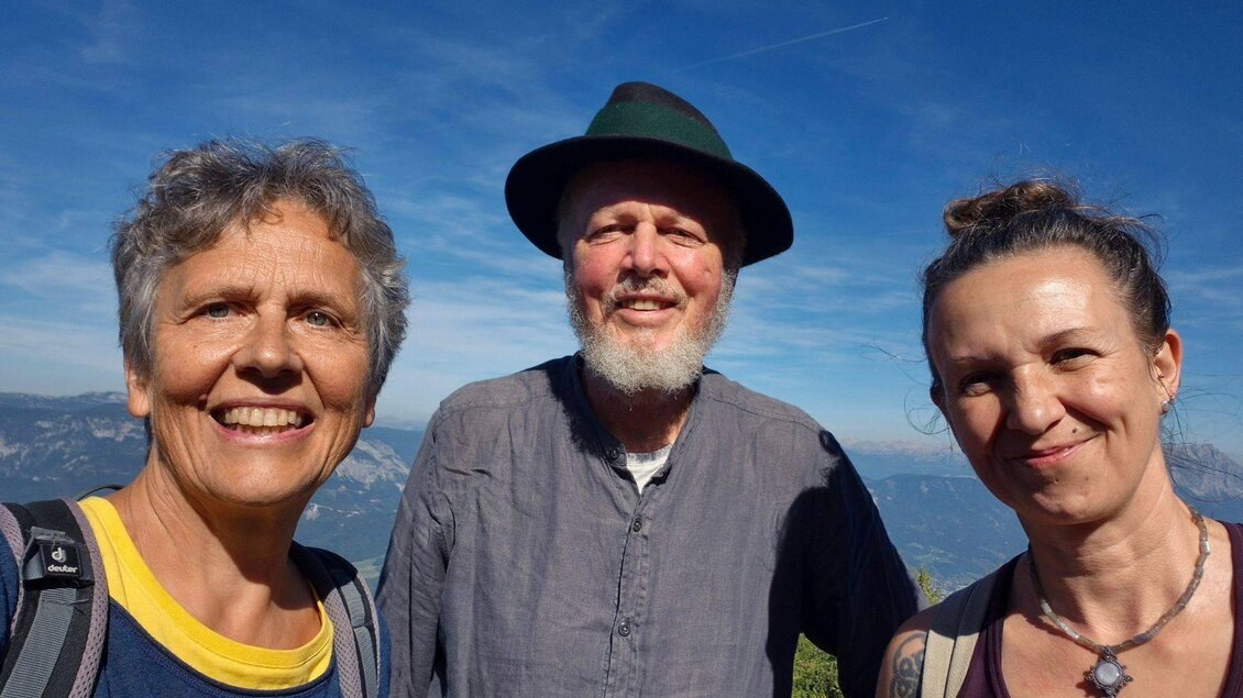 <p>Die drei Mitglieder vom Hinterberg Gsang posieren fröhlich vor einer schönen Berglandschaft. Der Himmel ist blau und die Umgebung wirkt malerisch.</p> | © Hinterberg Gsang
