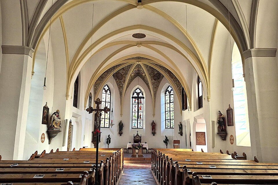 <p>Der Innenraum der Altausseer Pfarrkirche mit hohen Gewölben und bunten Fenstern. Bänke sind hintereinander aufgestellt und einige Figuren sind an den Wänden zu sehen.</p> | © Baumgartner Monika