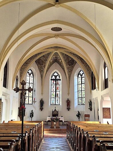 <p>Der Innenraum der Altausseer Pfarrkirche mit hohen Gewölben und bunten Fenstern. Bänke sind hintereinander aufgestellt und einige Figuren sind an den Wänden zu sehen.</p> | © Baumgartner Monika