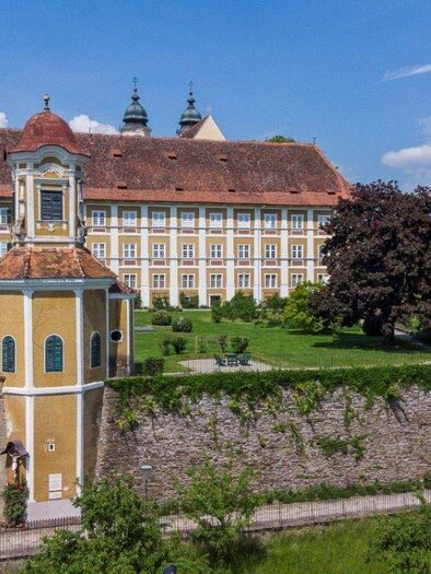 Ein historisches Gebäude mit einem großen, gepflegten Garten und zwei markanten Türmen. Die Architektur ist beeindruckend und umgeben von grüner Natur. | © Forstverwaltung Schloss Stainz