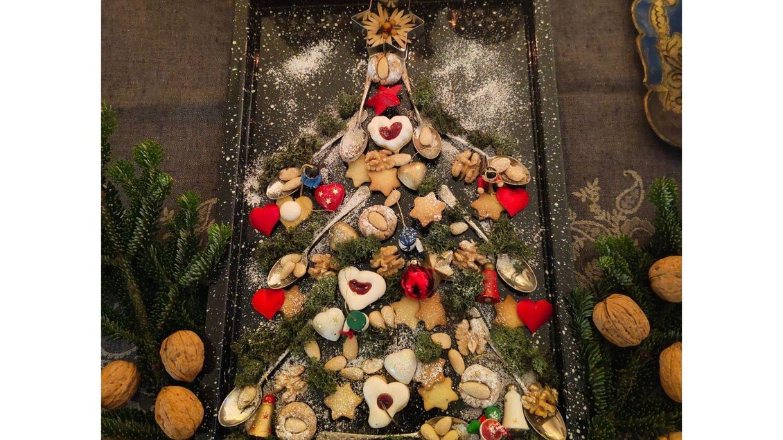 Ein dekorierter Weihnachtsbaum aus Gebäck und Nüssen auf einem Tablett. Der Baum ist mit roten und grünen Akzenten geschmückt. | © Podenhaus, Bad Aussee