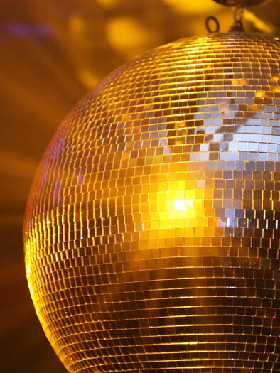A sparkling disco ball reflects warm light. The background radiates with gentle color play. | © pixabay