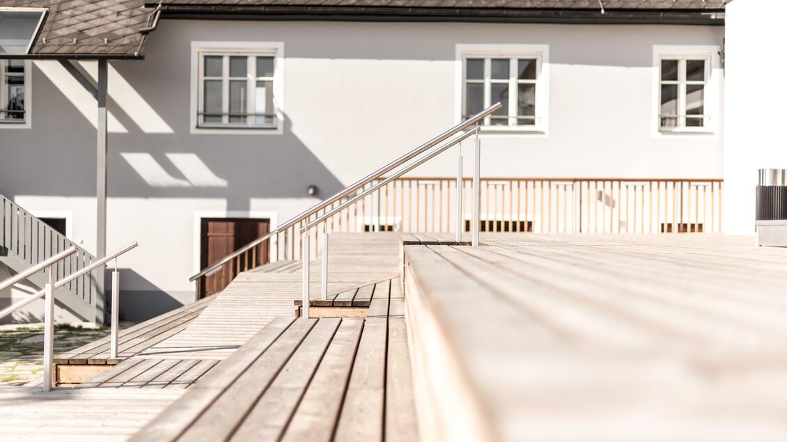 Ein schmaler Weg durch einen grünen Wald mit hohen Bäumen. Das Sonnenlicht fällt sanft auf den Weg und die Umgebung ist ruhig und friedlich. | © Stieglerhaus Blendpunkt