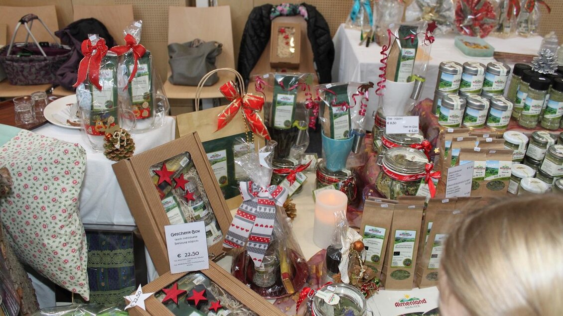 Ein farbenfrohes Weihnachtsmarkt-Setup mit vielen Geschenken und Produkten in dekorativen Verpackungen. Verschiedene Köstlichkeiten und dekorative Artikel sind auf einem Tisch ausgestellt. | © Gemeinde Gasen