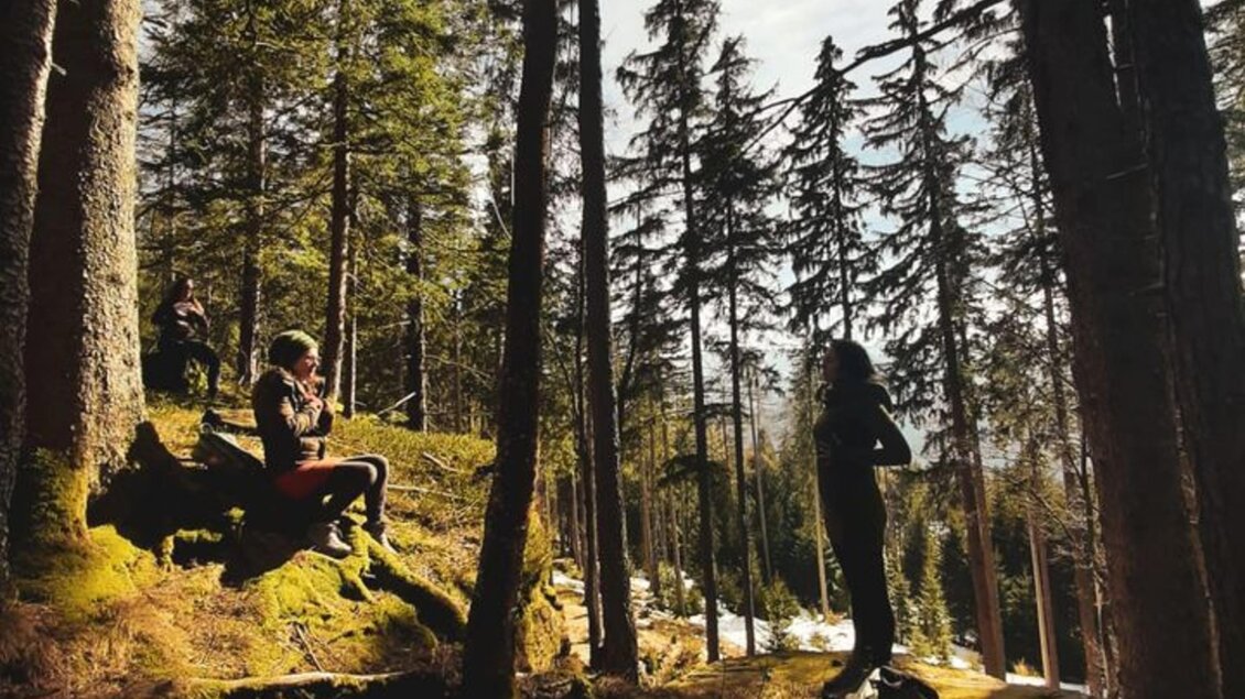 Ein ruhiger Wald mit hohen Bäumen und weichem Moos. Zwei Personen genießen die Natur und die frische Luft. | © Sabrina Lukas
