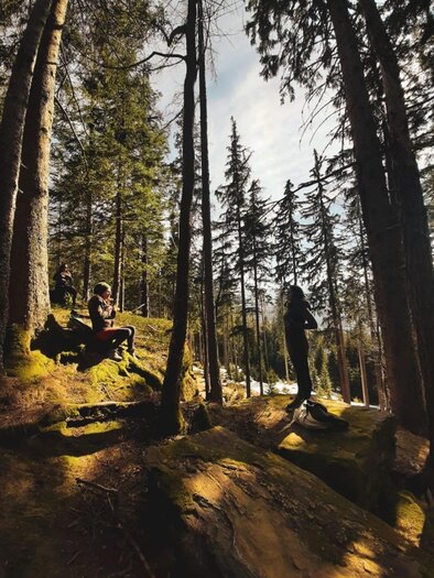 Ein ruhiger Wald mit hohen Bäumen und weichem Moos. Zwei Personen genießen die Natur und die frische Luft. | © Sabrina Lukas