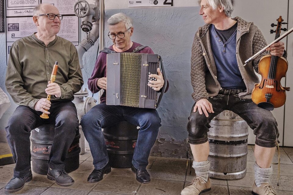 Drei Männer sitzen auf Fässern und spielen gemeinsam Musik. Einer spielt Flöte, einer ein Akkordeon und der dritte eine Geige. | © Kranzlbinder