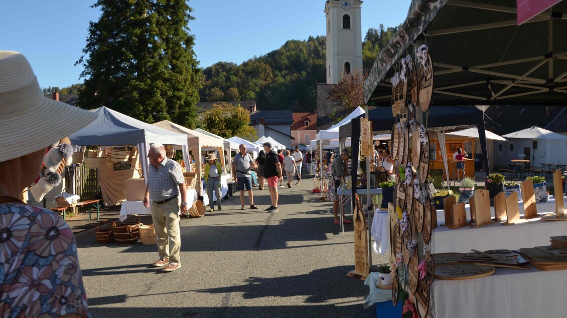 Ein basarähnlicher Markt mit Ständen und Besuchern. Im Hintergrund ist eine Kirche und grüne Hügel zu sehen. | © Forum Arnfels