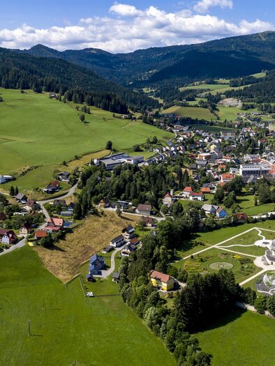 Eine malerische Landschaft mit sanften Hügeln und üppigen Wiesen. Im Hintergrund ist ein historisches Gebäude und ein schön angelegter Garten zu sehen. | © Tv Murau