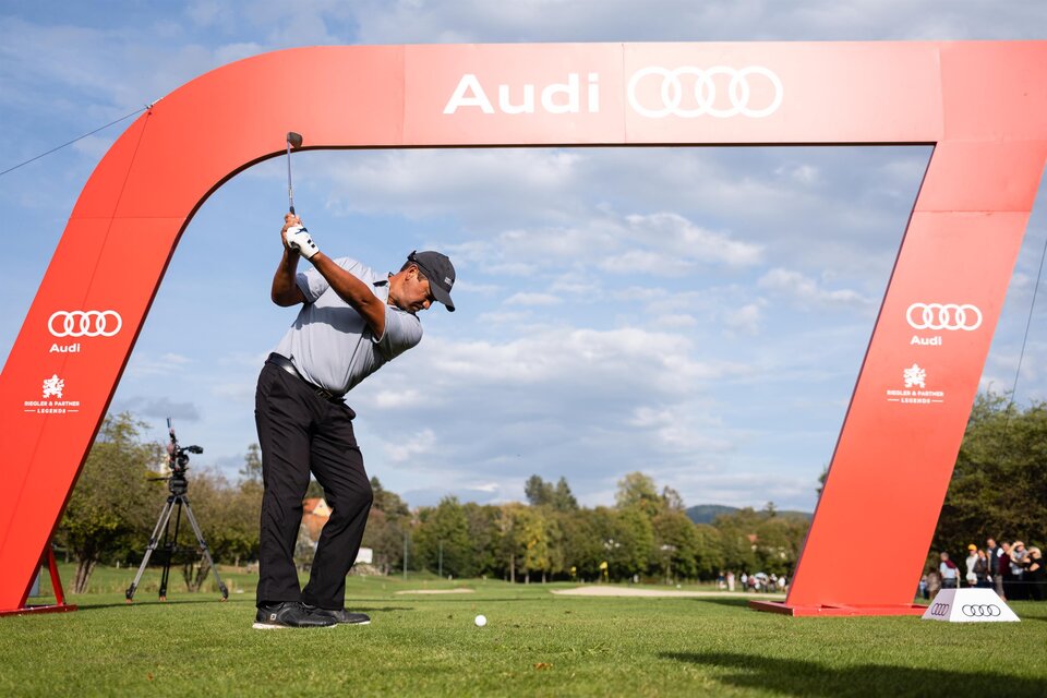 Ein Golfer schlägt vor einem großen Audi-Bogen auf einem Golfplatz ab. Im Hintergrund sind Zuschauer und ein klarer Himmel zu sehen. | © GEPApictures