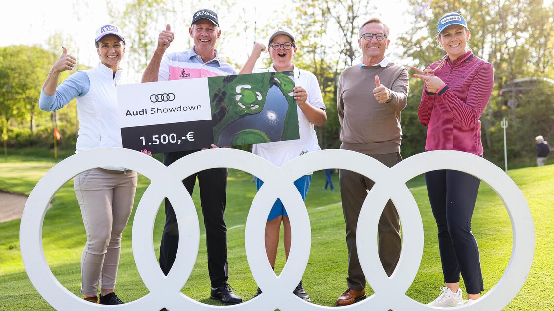 Eine Gruppe von fünf Personen posiert auf einem Golfplatz. Sie zeigen einen großen Scheck über 1.500 € für das Audi Showdown-Event. | © GEPApictures