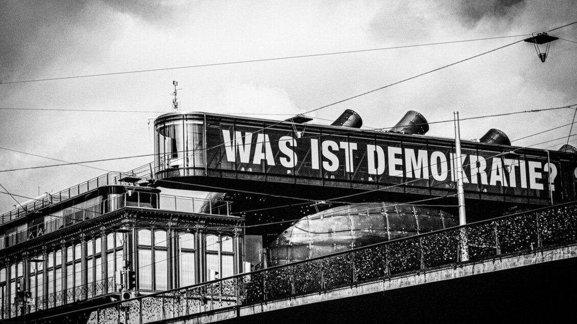 Historische Schwarz-Weiß-Aufnahme des Kunsthaus Graz mit dem Schriftzug „Was ist Demokratie?“ | © Bernd Grosseck