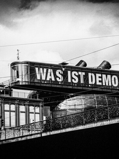 Historische Schwarz-Weiß-Aufnahme des Kunsthaus Graz mit dem Schriftzug „Was ist Demokratie?“ | © Bernd Grosseck
